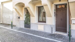 A building with a brown door, a window with a sign, and a potted plant. - Castelmenardo39 (Treviso)