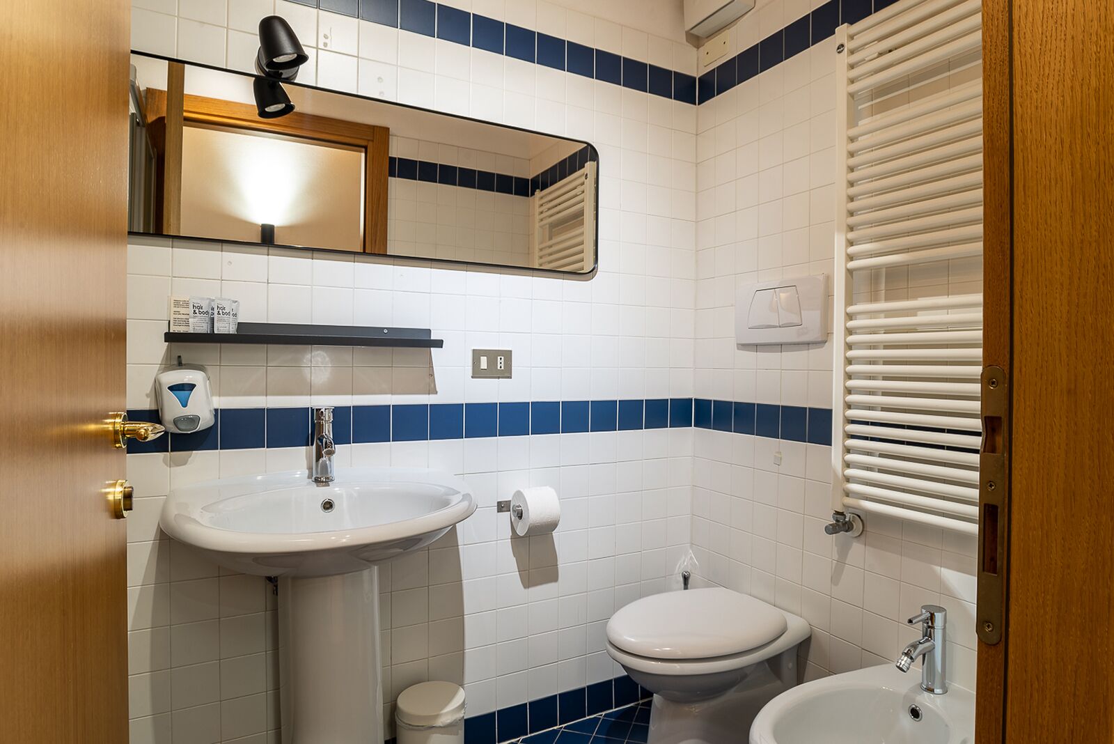 Ein Badezimmer mit Waschbecken, Toilette, Bidet und Spiegel.