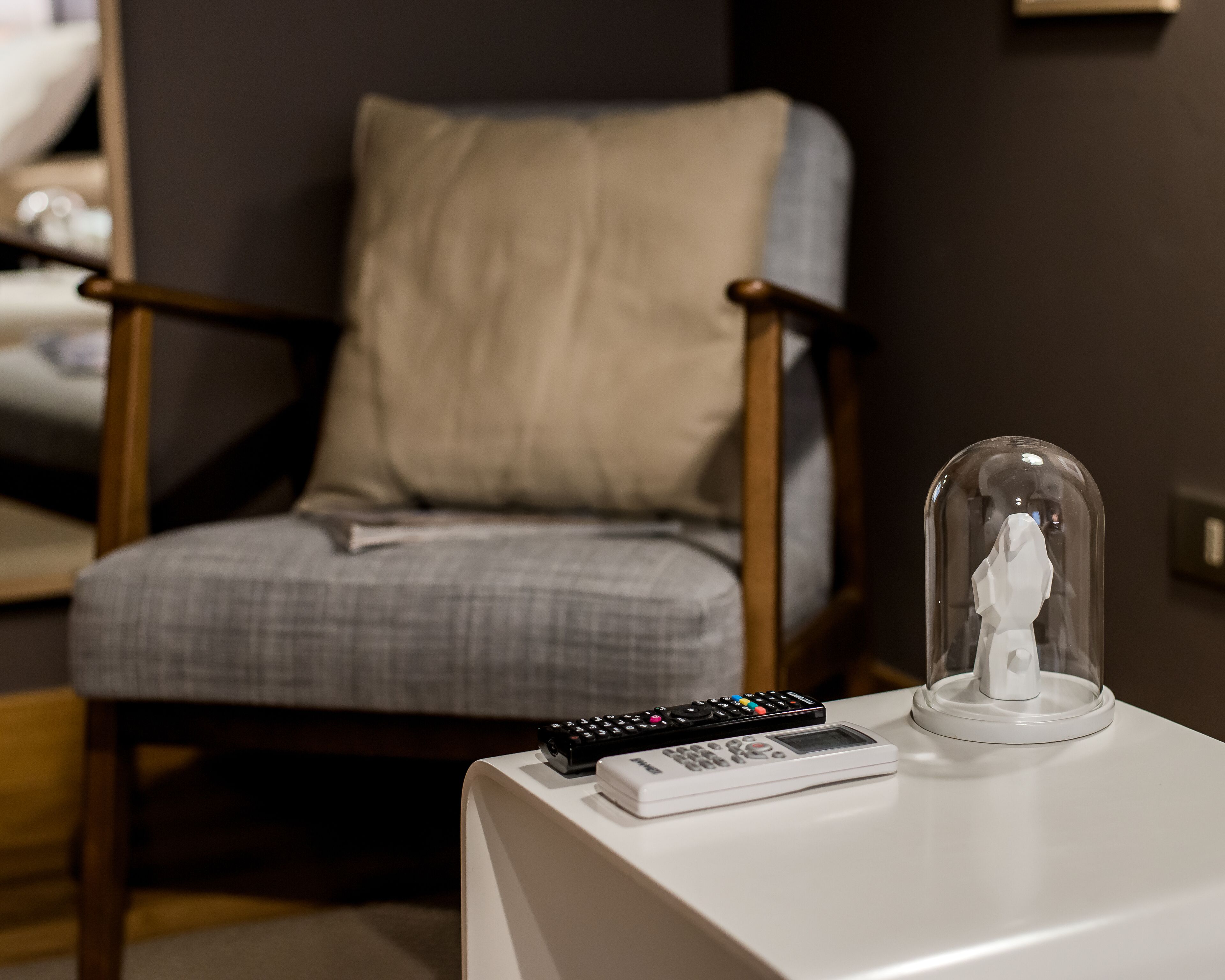 Una mesa blanca con un control remoto y una cúpula de vidrio.