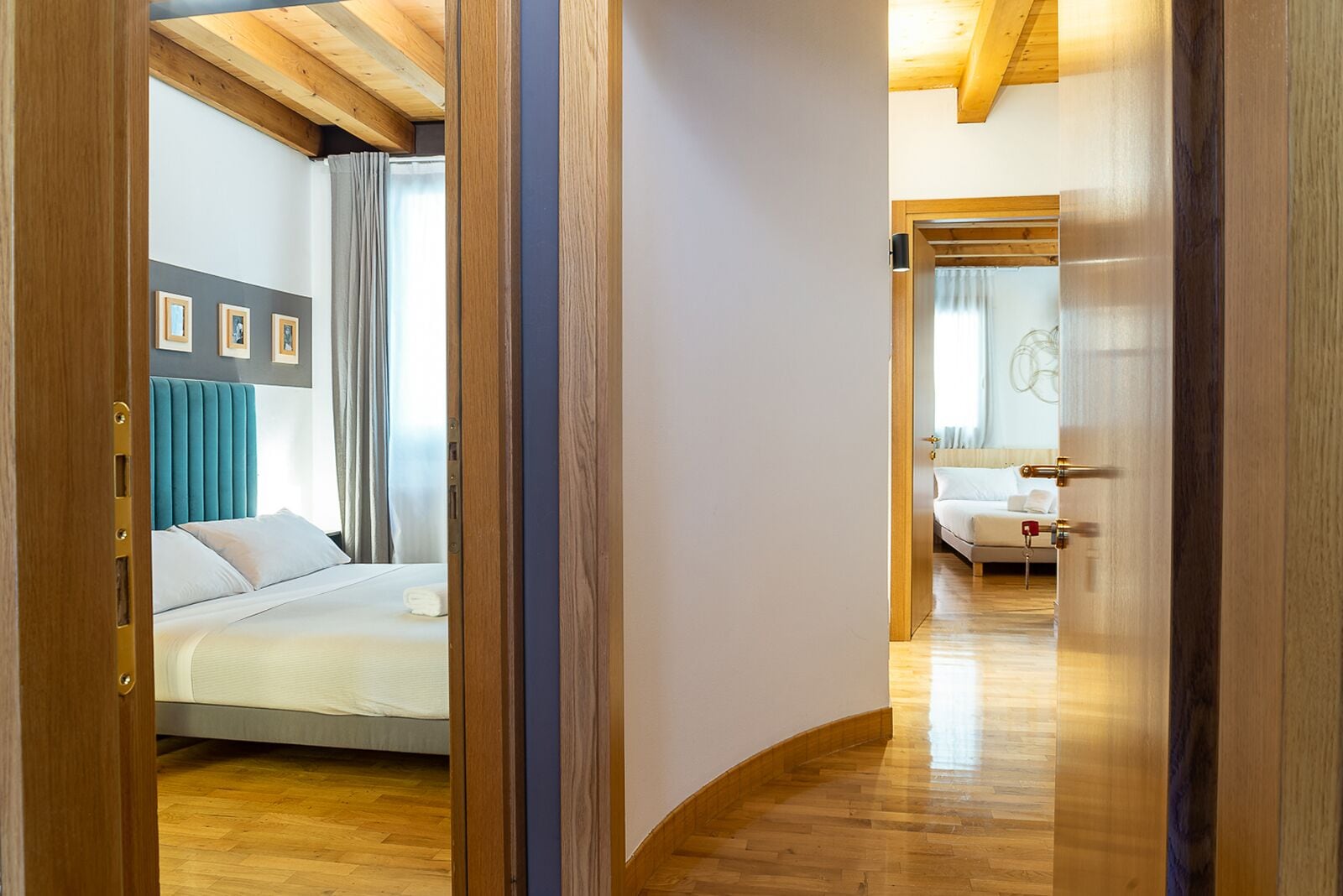 Une chambre d’hôtel avec un lit, une salle de bain avec un miroir et un couloir menant à une autre pièce.