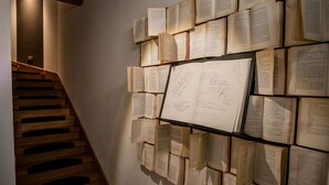 A wall of open books arranged in a grid pattern, with a staircase on the left. - Castelmenardo39 (Treviso)