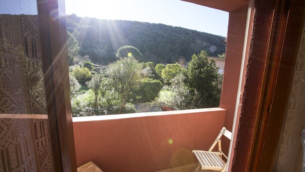 A balcony with a view of a forested hillside and a river.