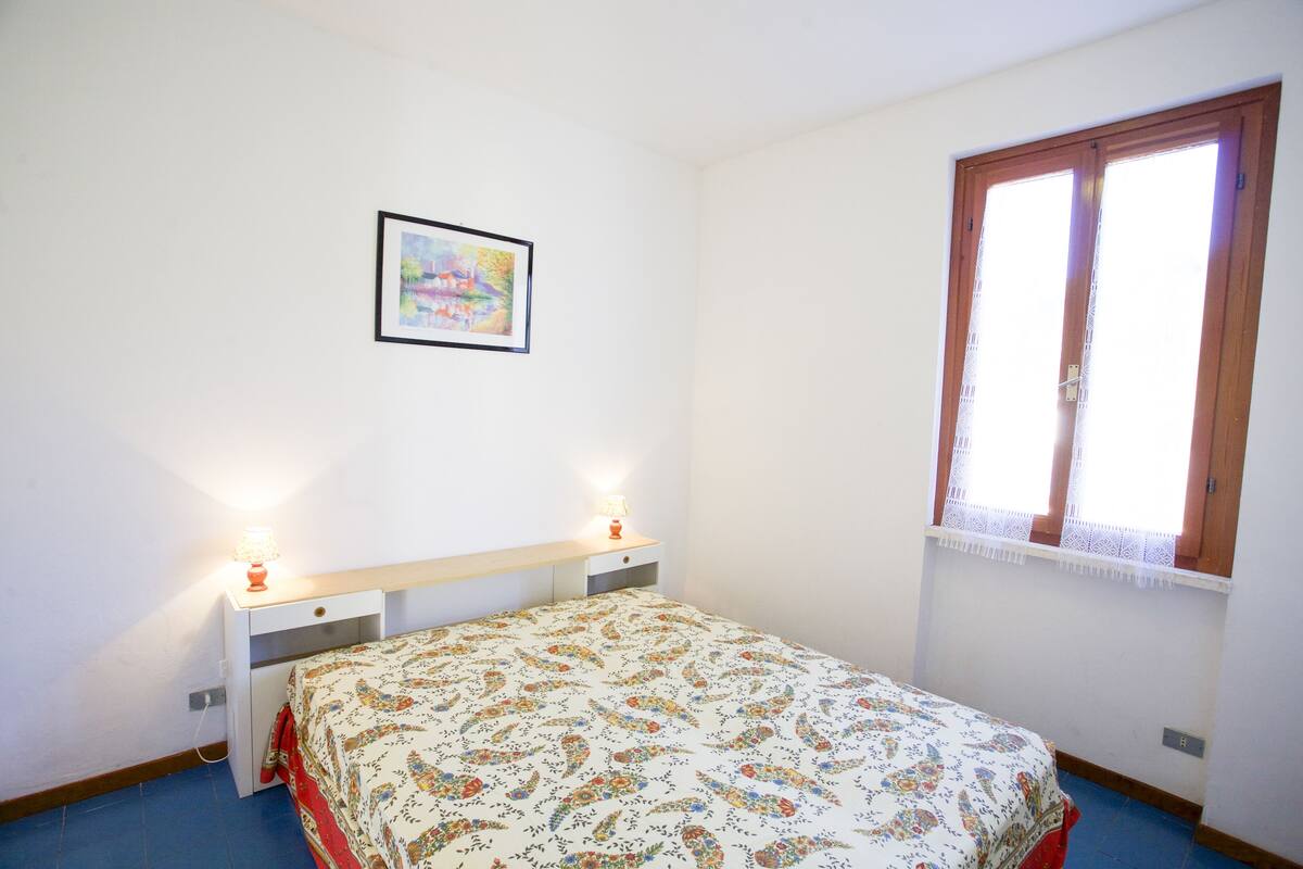 Une chambre à coucher avec un lit, des tables de chevet, une fenêtre et un tableau accroché au mur.