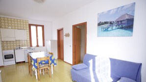 A compact living space with a dining area, kitchenette, and a sofa.