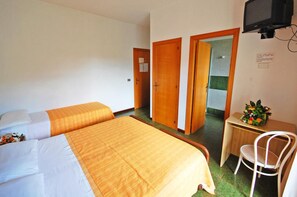 Habitación de hotel con dos camas, un escritorio, una silla y un televisor.