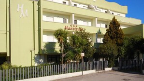 A hotel named "Maestrale" with a green facade, multiple floors, and a prominent sign.