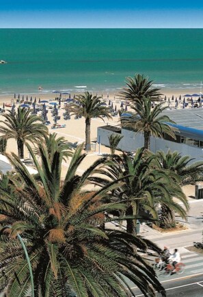 A beach with palm trees, umbrellas, and a clear view of the ocean. - Hotel Maestrale (San Benedetto del Tronto)