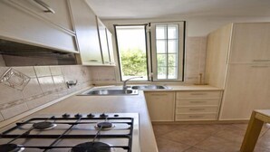 A kitchen with a gas stove, sink, and cabinets. - Appartamenti Loredana (Capoliveri)