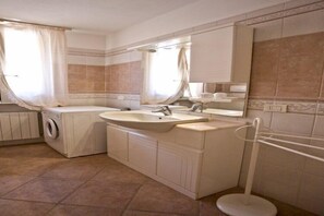 A bathroom with a sink, mirror, and a washing machine. - Appartamenti Loredana (Capoliveri)