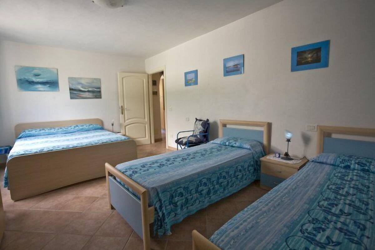 Een slaapkamer met twee eenpersoonsbedden, een stoel en een nachtkastje met een lamp.