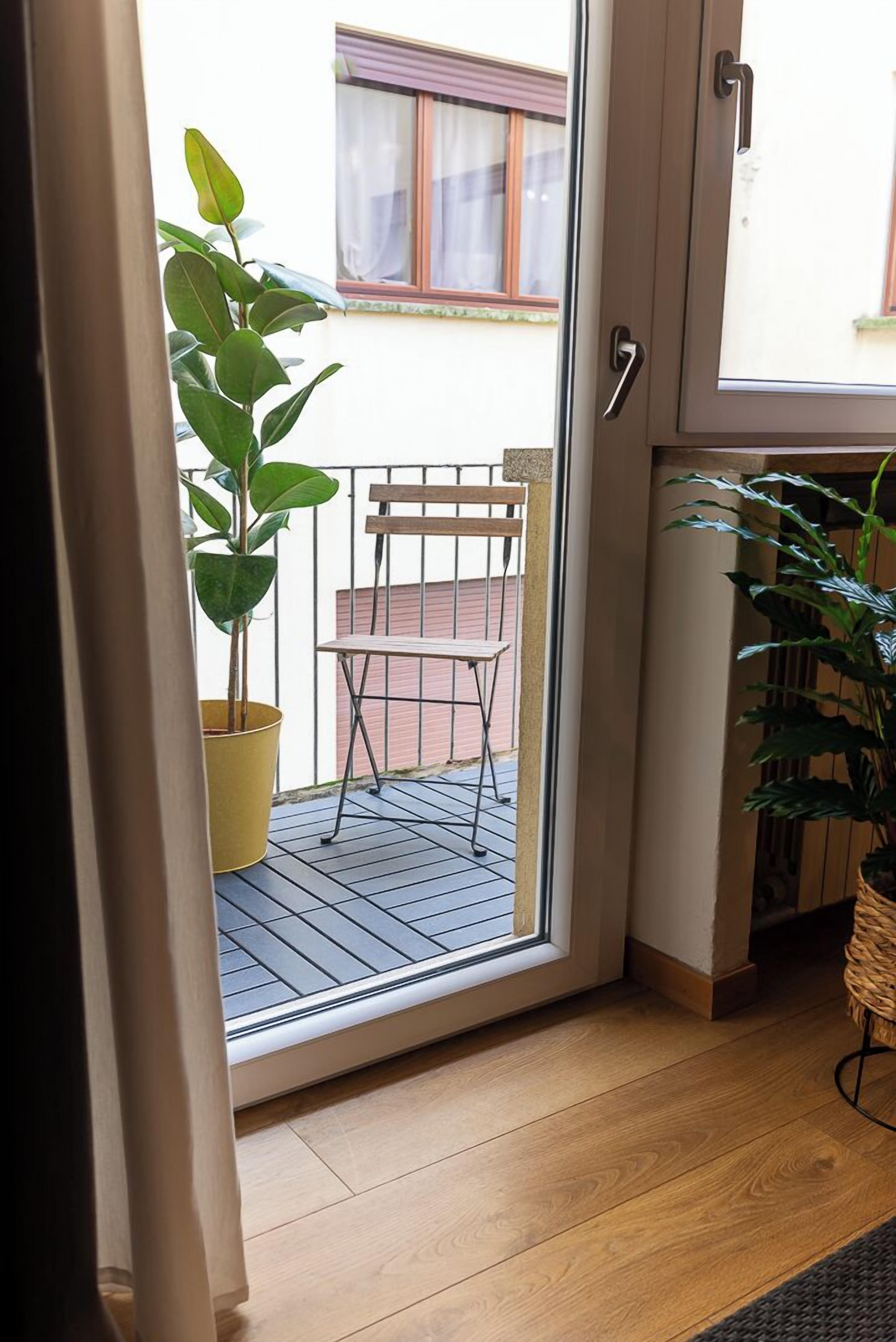 A room with a sliding glass door leading to an outdoor balcony with a chair and a potted plant.
