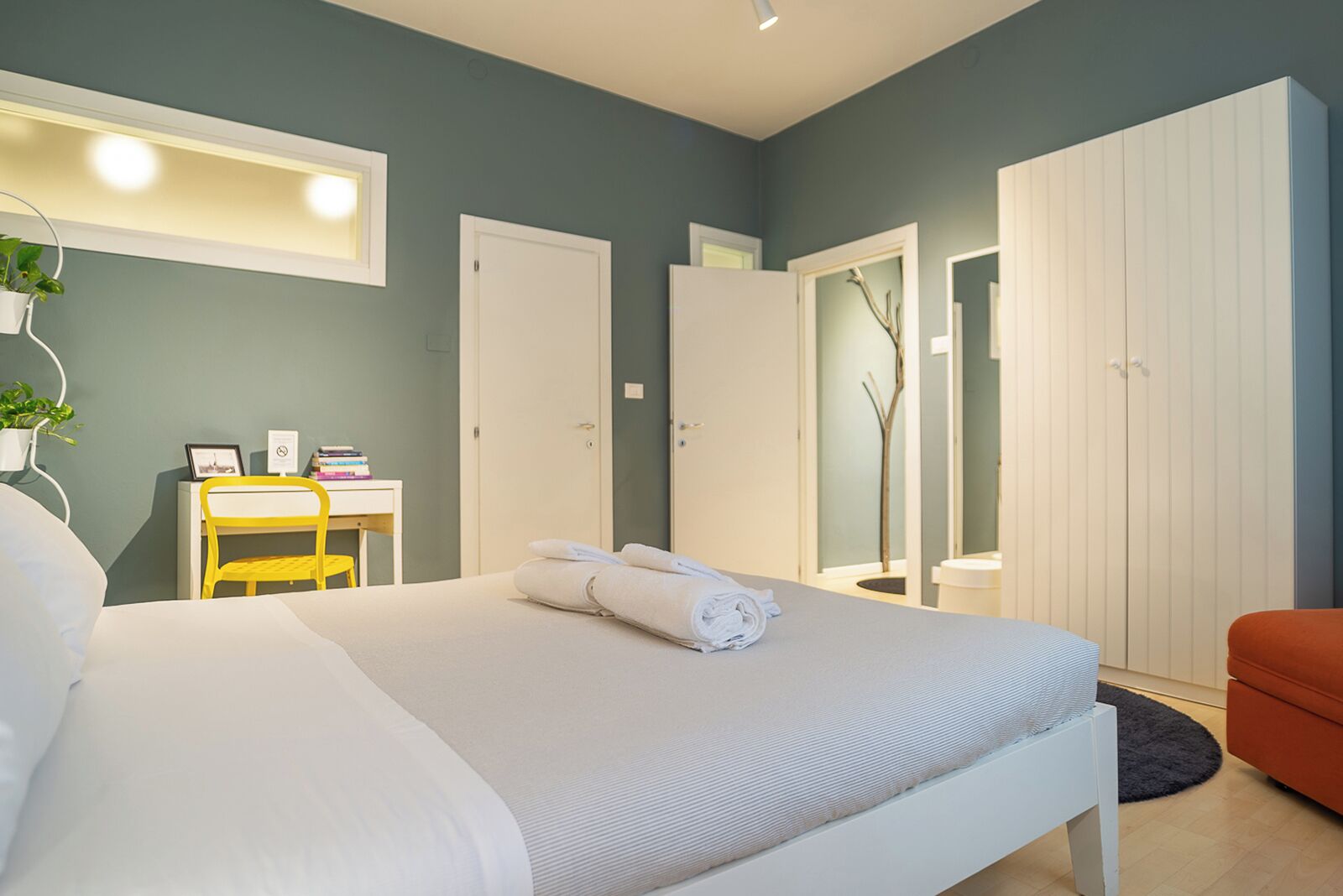 A neatly arranged bedroom with a bed, a desk, and a wardrobe.