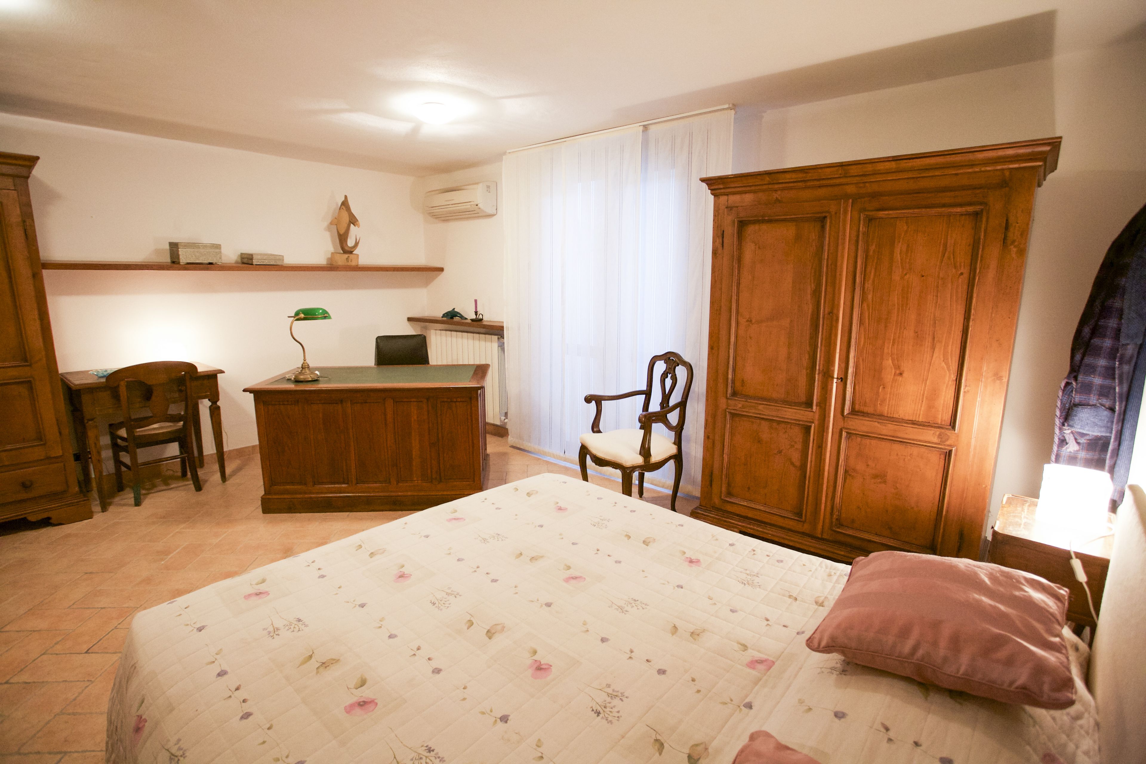 A bedroom with a bed, a desk, a chair, and a wardrobe.