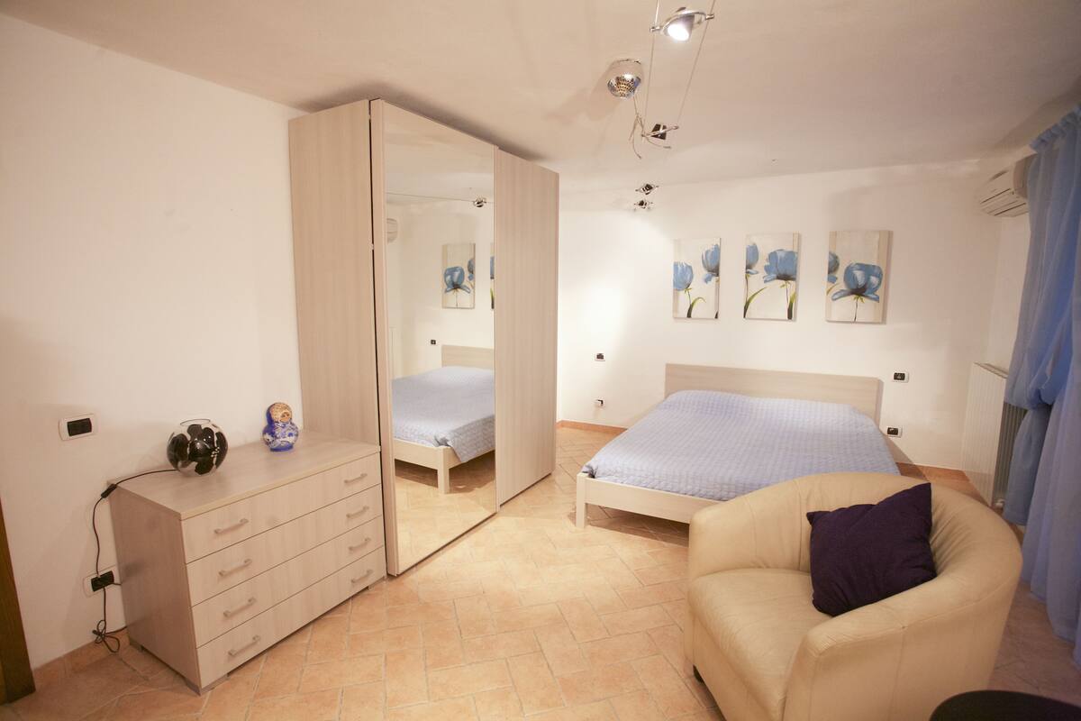Ein Schlafzimmer mit Bett, Kommode, Stuhl und Spiegel.