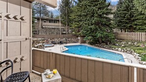 Ein Garten mit Swimmingpool, einer Holzterrasse und einer Steinmauer.