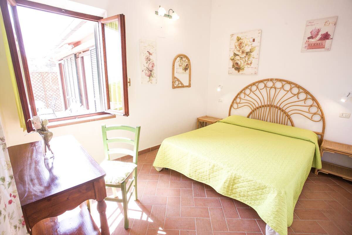 A bedroom with a bed, a chair, a table, and a window.