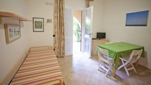 A room with a bed, a dining table with chairs, a TV, and a door leading outside. - Appartamenti Nisportino (Rio)