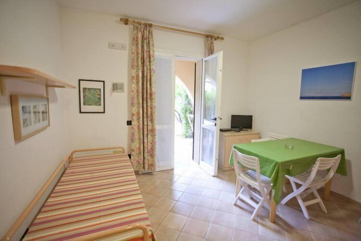 A room with a bed, a dining table with chairs, a TV, and a door leading outside.