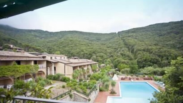 A hotel with a pool, surrounded by lush greenery and hills in the background. - Appartamenti Nisportino (Rio)