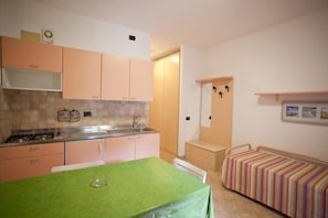 A compact kitchen with a dining table, a small bench, and a kitchenette.