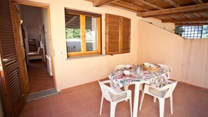 Un comedor con una mesa preparada para cuatro, contraventanas de madera y vistas al jardín a través de una ventana.