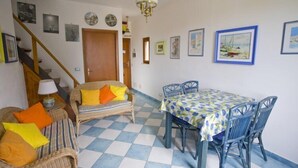 A dining area with a checkered floor, wicker furniture, and a table with a patterned tablecloth. - Appartamento Casa Paoletta (Rio)