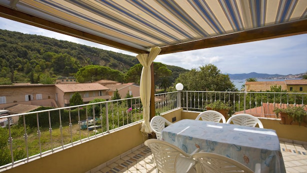 A balcony with a table and chairs, overlooking a scenic view of a hillside and a body of water. - Appartamento Casa Paoletta (Rio)