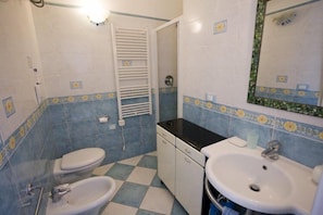 A bathroom with a white toilet, a bidet, a sink, and a mirror.