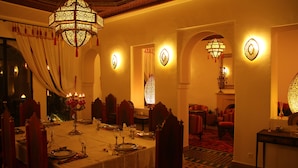 Un comedor con una larga mesa dispuesta para una comida, candelabros ornamentales y decoración tradicional.