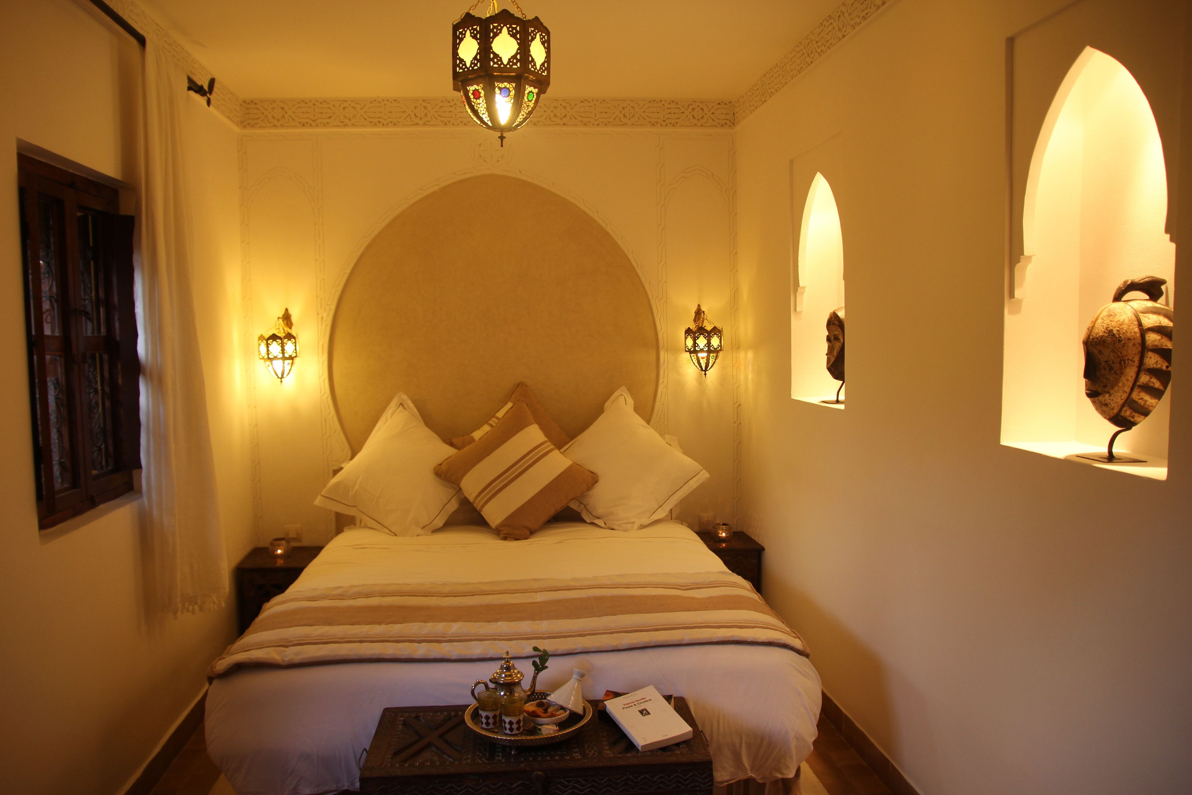 A hotel room with a large bed, two wall-mounted lamps, and a decorative ceiling light.