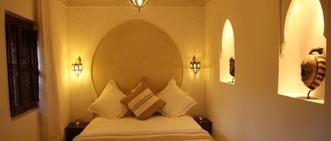 A hotel room with a large bed, two wall-mounted lamps, and a decorative ceiling light.
