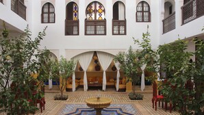 Un patio con una fuente, zona de estar y arcos decorativos.