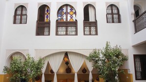 Un patio con zona de estar, arcos y ventanas decorativas.