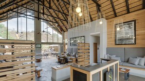 A spacious, modern interior with wooden furniture, a reception desk, and large windows allowing natural light.