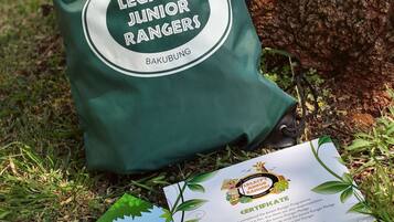 Un sac vert portant l’inscription « Legacy’s Junior Rangers Bakubung » et un certificat posé sur l’herbe.