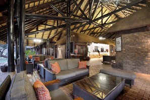 A spacious lounge area with high ceilings and exposed beams, featuring comfortable seating and a fireplace.