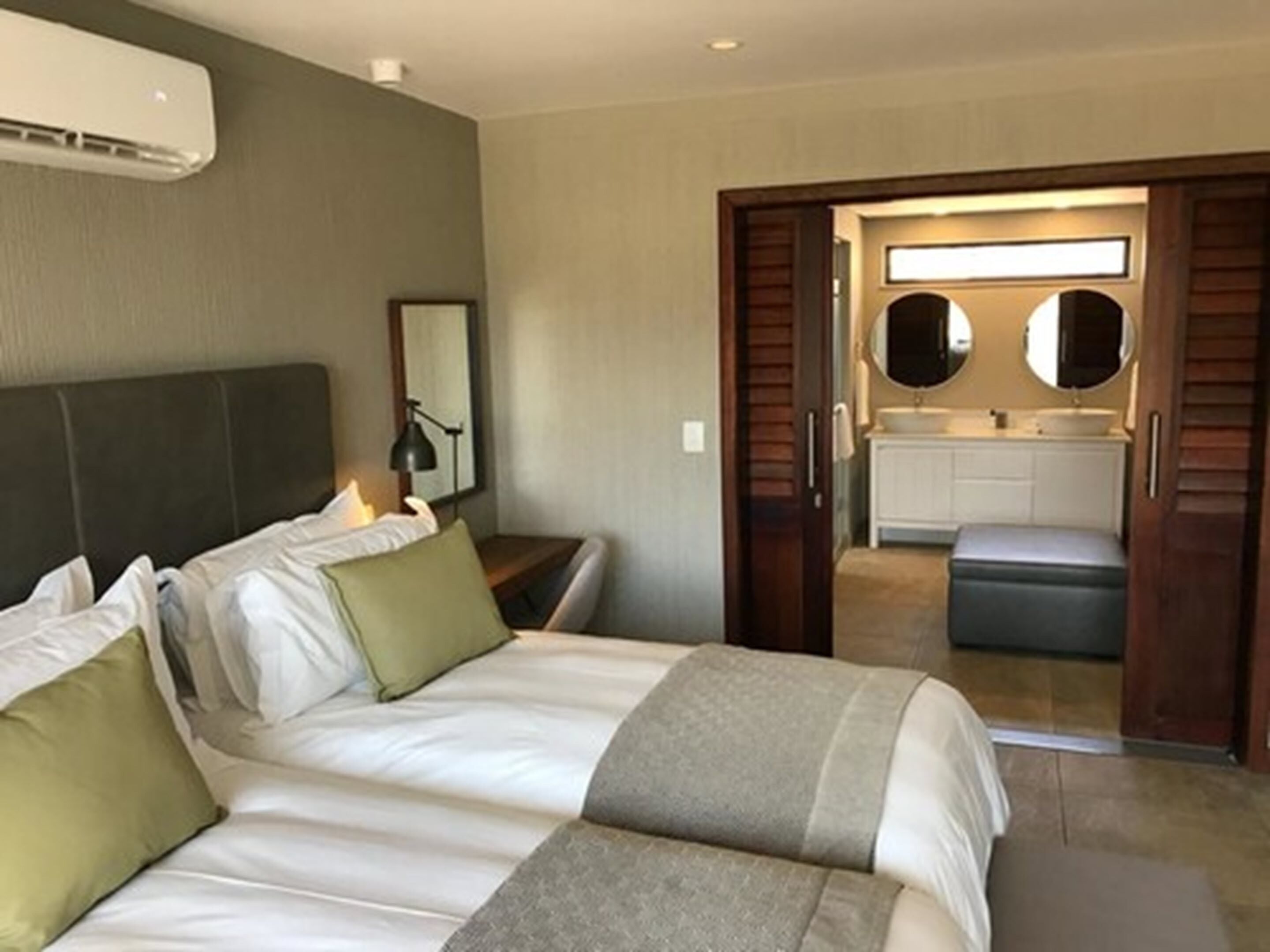 A hotel room with a large bed, bedside table, and a view into the bathroom through an open door.