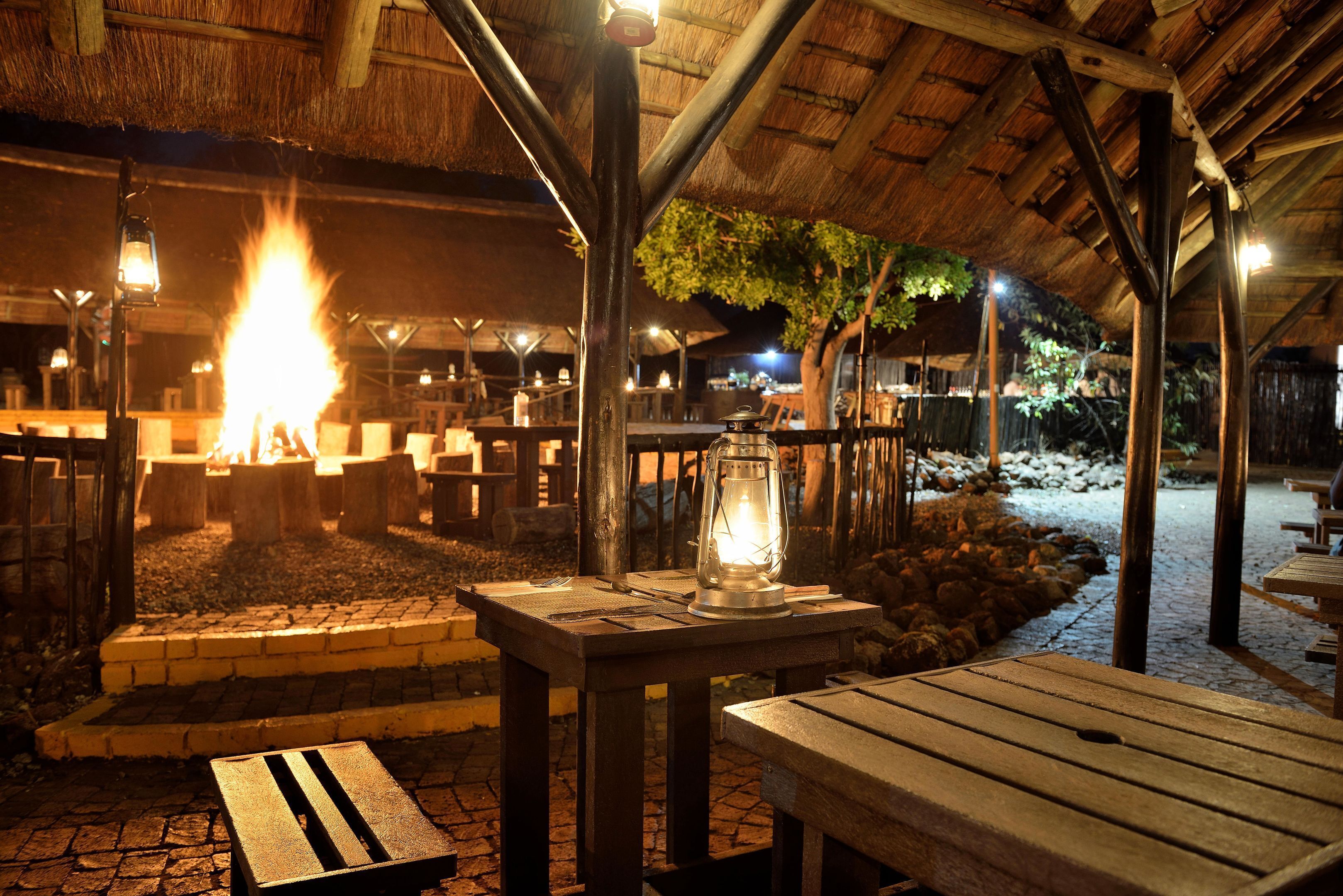 An outdoor dining area with a fire pit, wooden tables, and benches.
