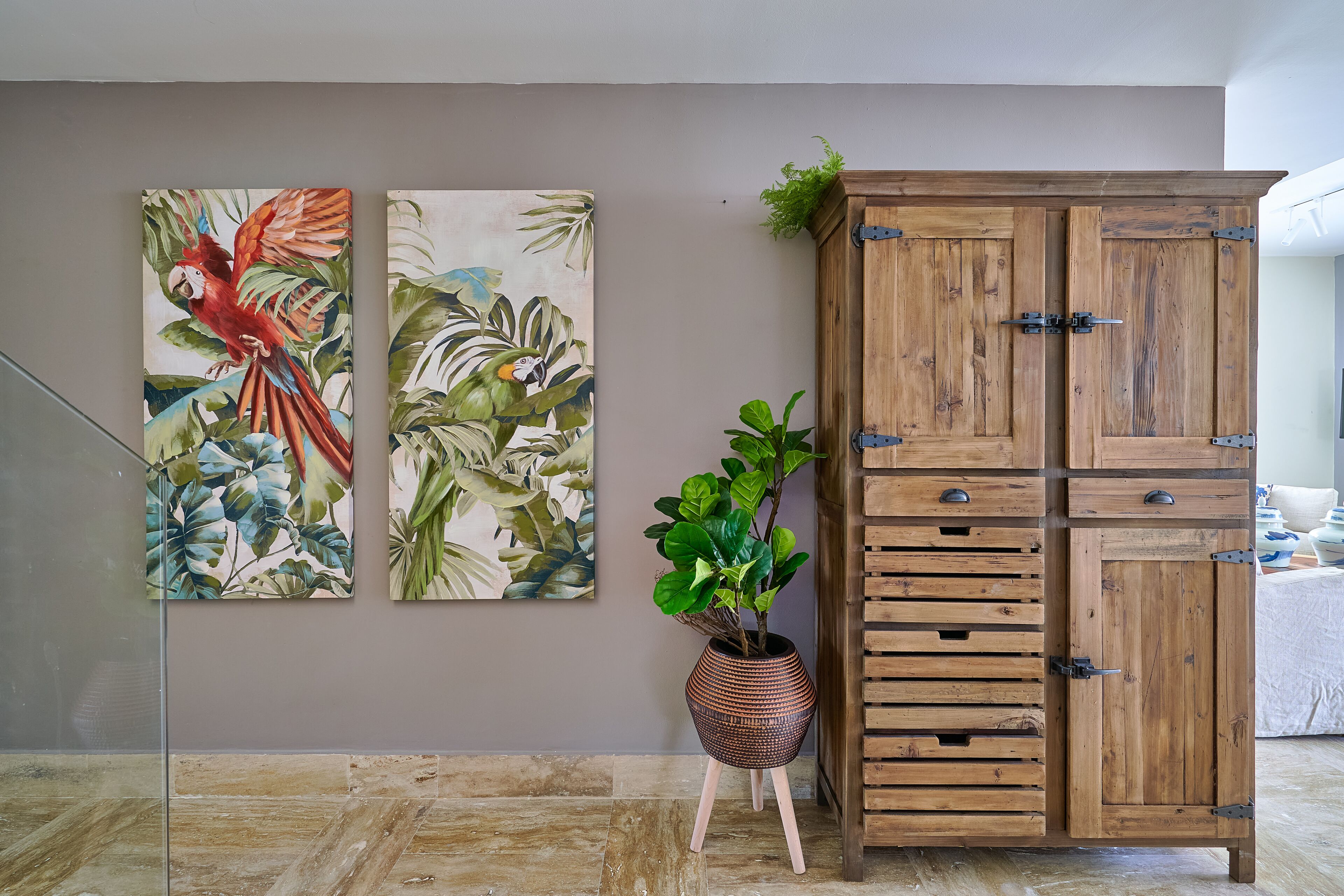 Een kamer met een houten kast, een potplant en twee wanddecoraties.