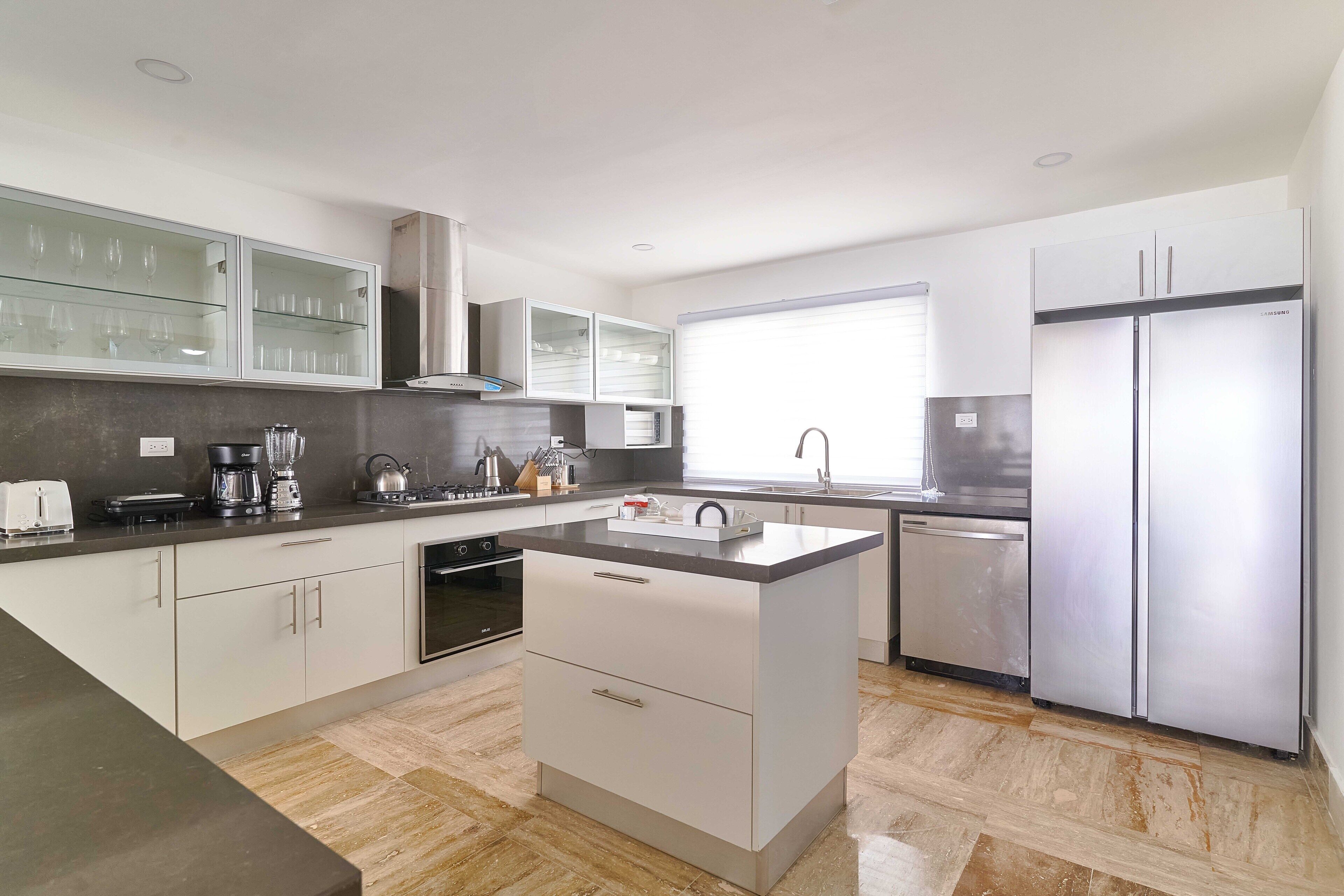 A modern kitchen with white cabinets, a stainless steel refrigerator, and a built-in oven.