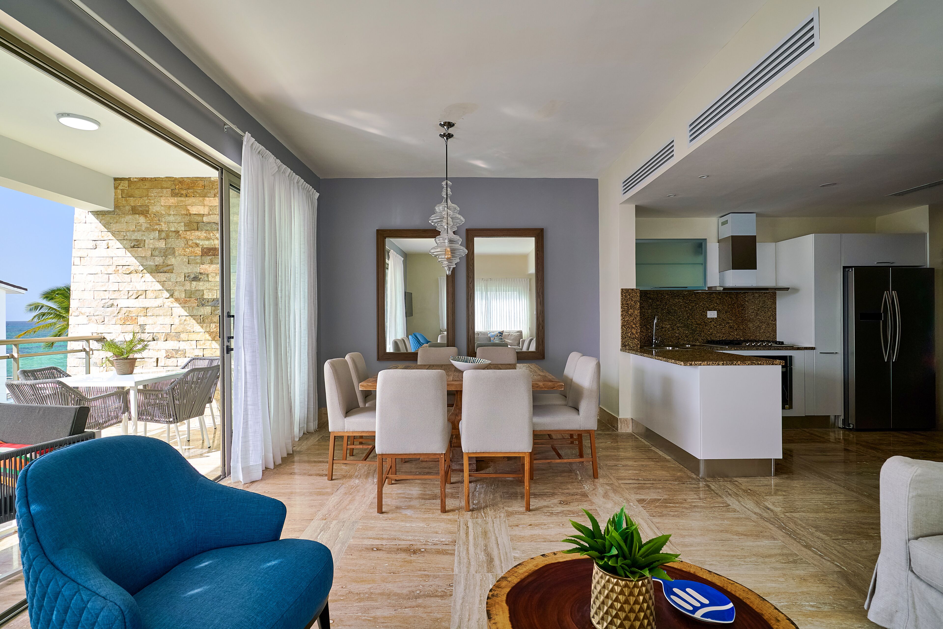 A modern living room with a dining area, a kitchen, and a balcony with a view.