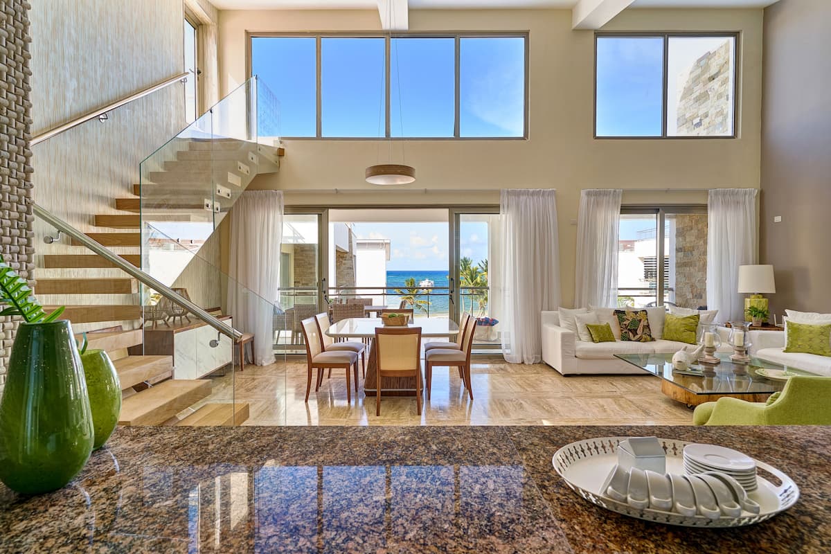 A spacious living area with a dining table, a sofa, and a view of the ocean.