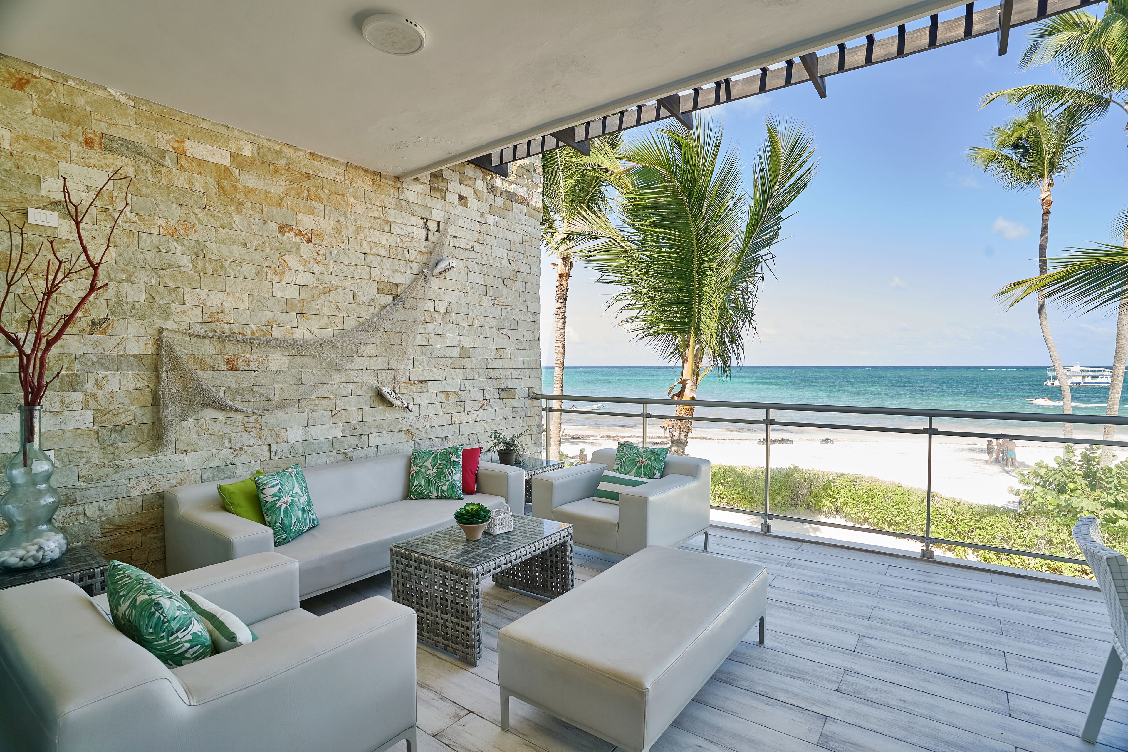 Una sala de estar moderna con pared de piedra, muebles blancos y vista al mar.