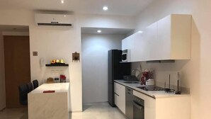 Una cocina moderna con armarios blancos, un refrigerador negro y un horno empotrado.