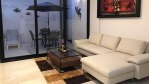 Una sala de estar moderna con un sofá blanco, una mesa de centro de vidrio y un comedor con sillas y una mesa.