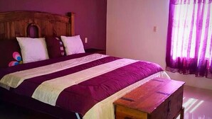 A bed with a wooden headboard, a purple and white striped bedspread, and a wooden nightstand. - Casa San Miguel 4479 (Mexico City)