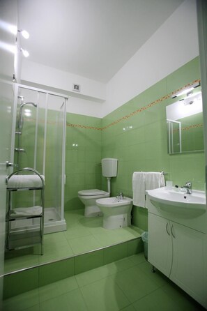 A bathroom with a shower, toilet, sink, and mirror.