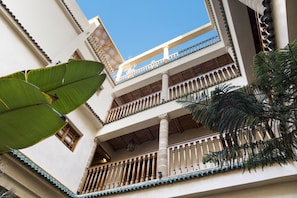 A multi-story building with balconies, columns, and a clear blue sky.