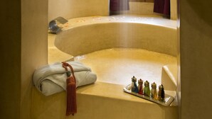 A spa room with a large bathtub, a window, and a towel rack with towels. - Riad Chbanate (Essaouira)