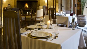 A dining area with a fireplace, arched ceiling, and a table set for a meal. - Riad Chbanate (Essaouira)